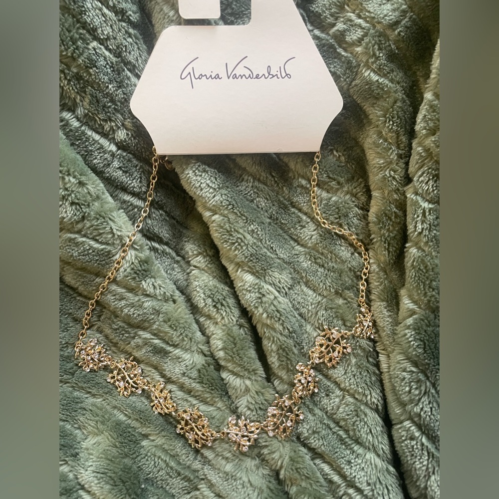 Gold necklace with scattered branch designs.